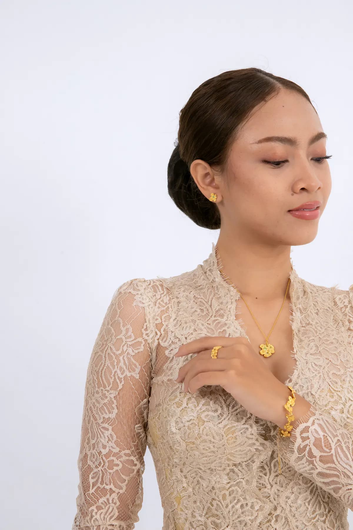 Model in a lace kebaya wearing a gold pendant necklace, ring and bracelet