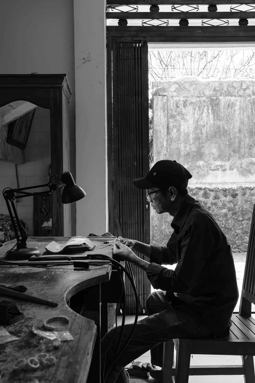 Black-and-white view of the artisan at his curved workbench